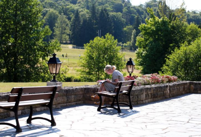 une dame lit un magazine sur un banc