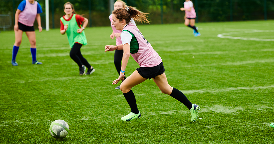 étudiante qui joue au football avec un maillot rose 