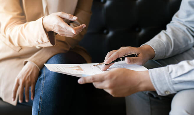 two professionals discussing graphs ©memyjo-AdobeStock