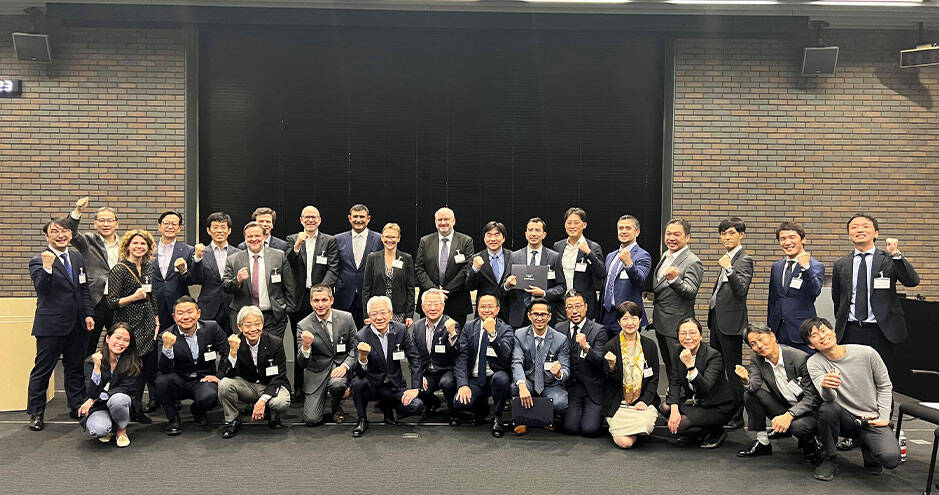 Large group of business people or professionals posing together, smiling and raising their arms in celebration or achievement