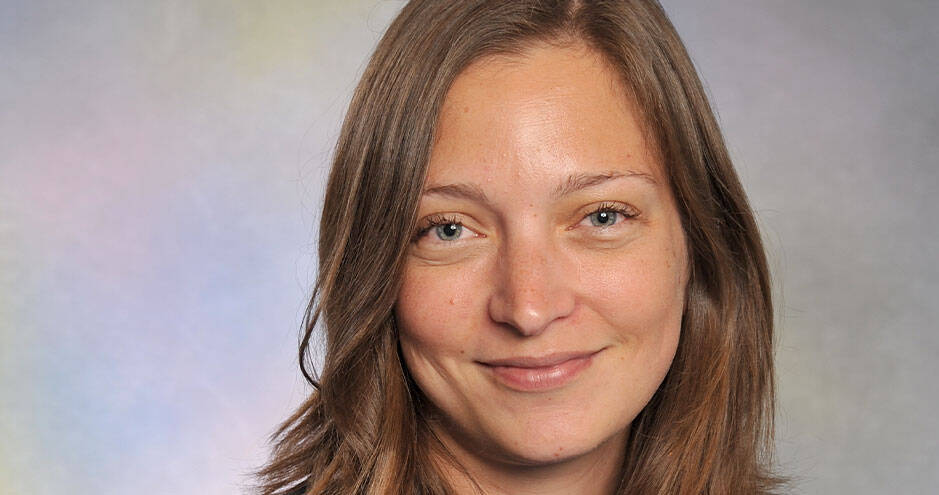 Headshot portrait of a smiling woman with long brown hair